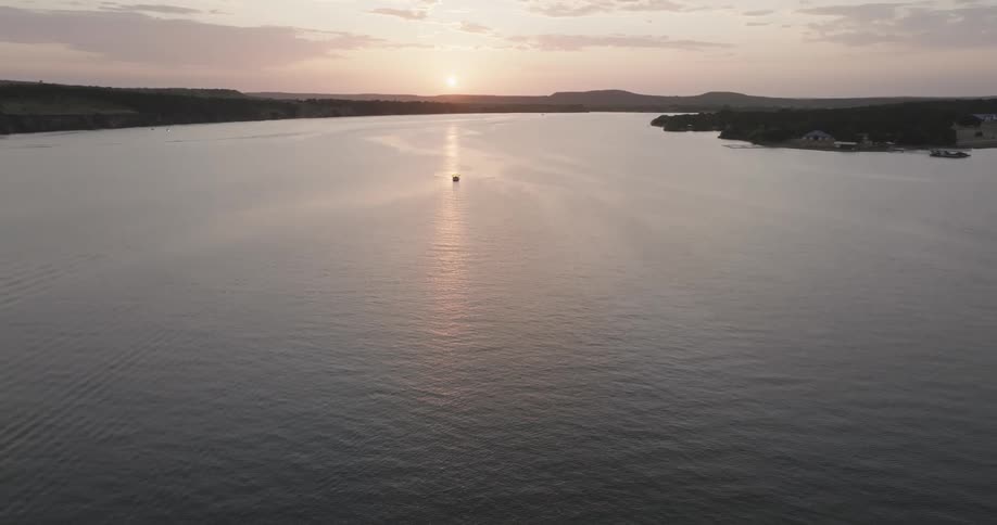 Aerial landscape of a river surrounded by vegetation with the sun on the horizon