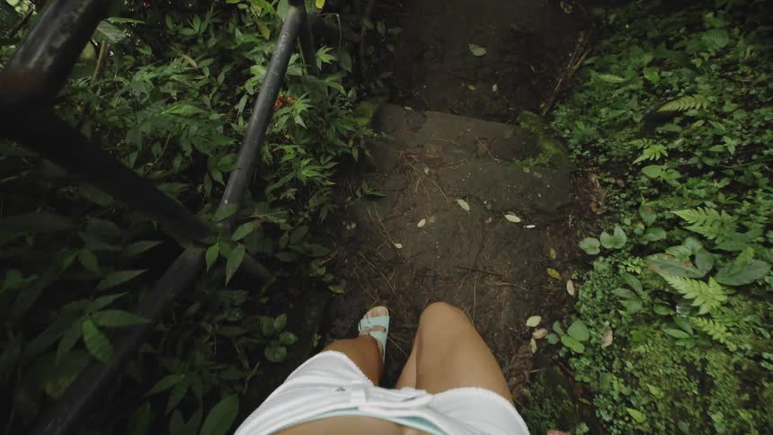 Woman point of view walking down the stairs in an outdoor location surrounded by vegetation
