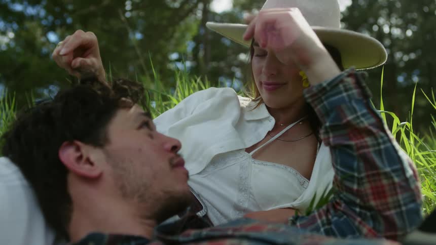 A man and woman are romantically playful in a grassy field