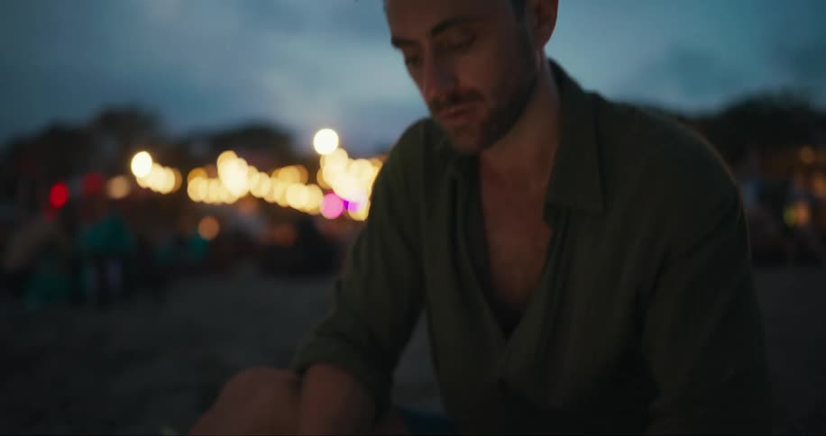 A man sitting on the beach is working on his laptop