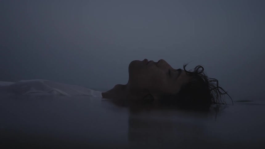Woman with eyes closed floating in calm water on a foggy day