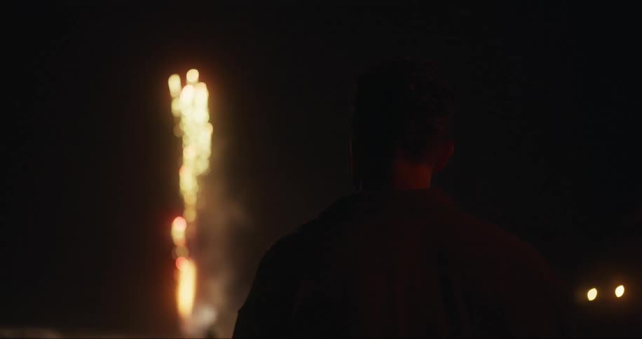 Silhouette of a man from behind watching the night sky with colorful fireworks