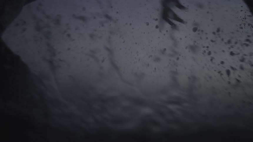 Silhouette of two adults running through the waters of the beach on a cloudy day