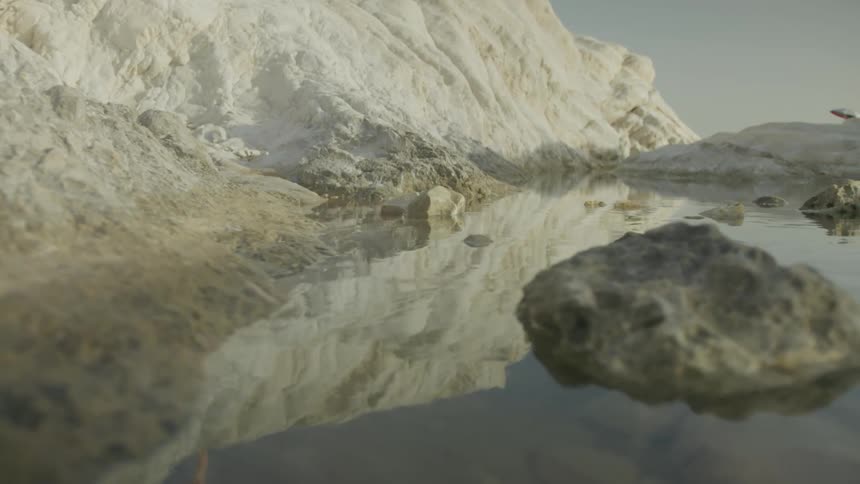 Calm lake in rocks by a whitehued mountain