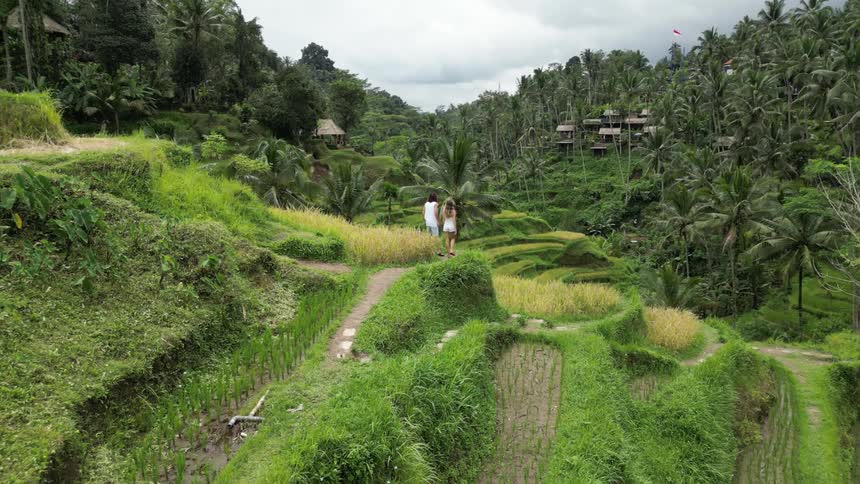 Man and woman walking together in an agricultural field amidst hills and mountains with tropical vegetation