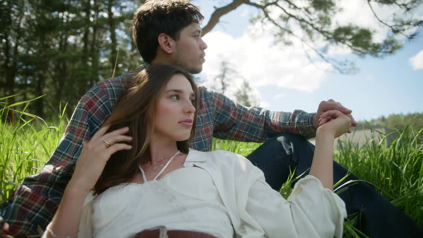 Woman lying in a field next to a man who is sitting