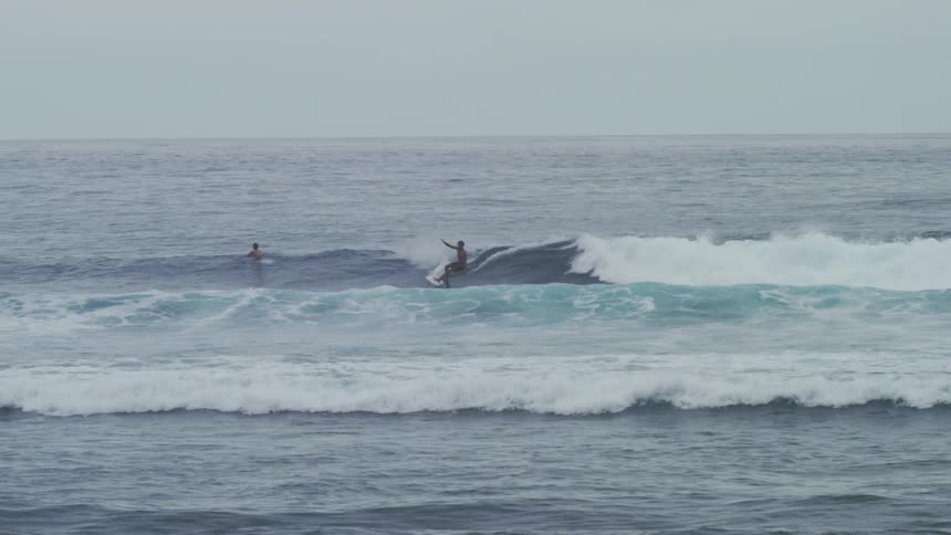 Person surfing a wave with other surfers in the sea