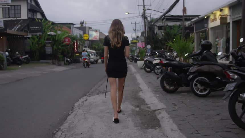 People ride their scooters past a woman walking