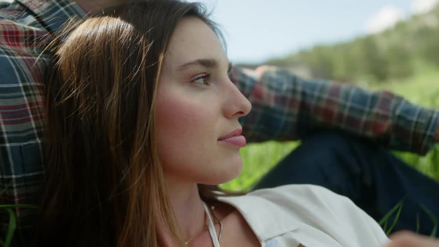 Portrait of a woman holding a yellow flower lying on a mans shoulder in a field