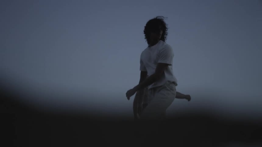 Two young men walking on the shallow water of a beach during twilight