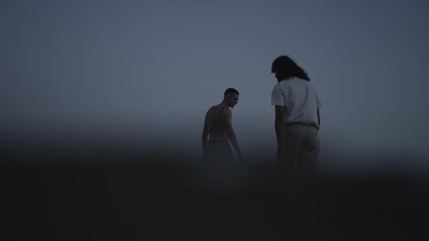 Two men walking in shallow water on a cloudy day