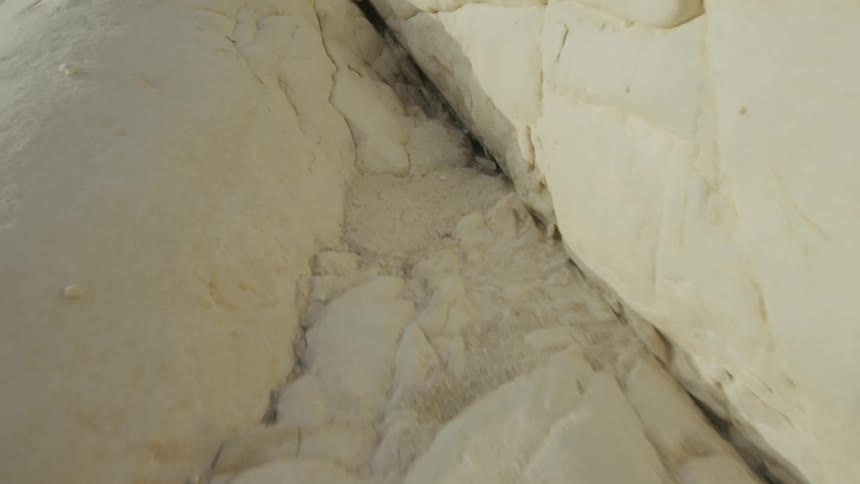 Close up view of jagged cracks on the surface of a white rock wall