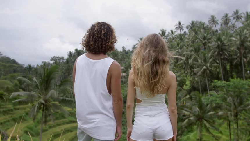 Back view of a man and a woman enjoying the view in a natural environment with tropical forests