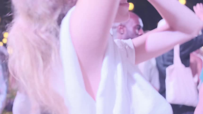 Woman enjoying and dancing in a club with lots of people and lights
