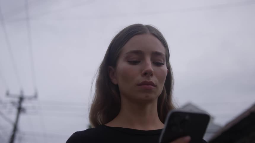 A young woman walks while reading from a smartphone