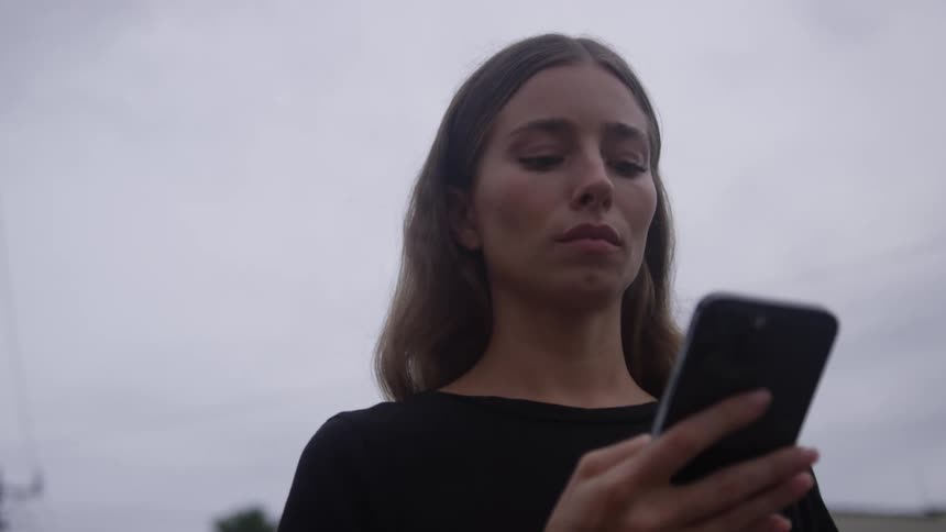 Female pedestrian scrolling on a smartphone looks up