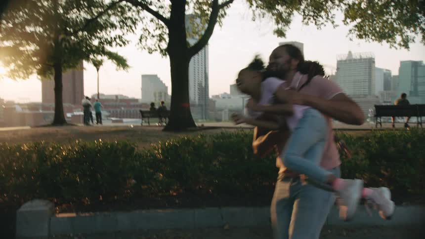 A family chase after each other while playing in the park