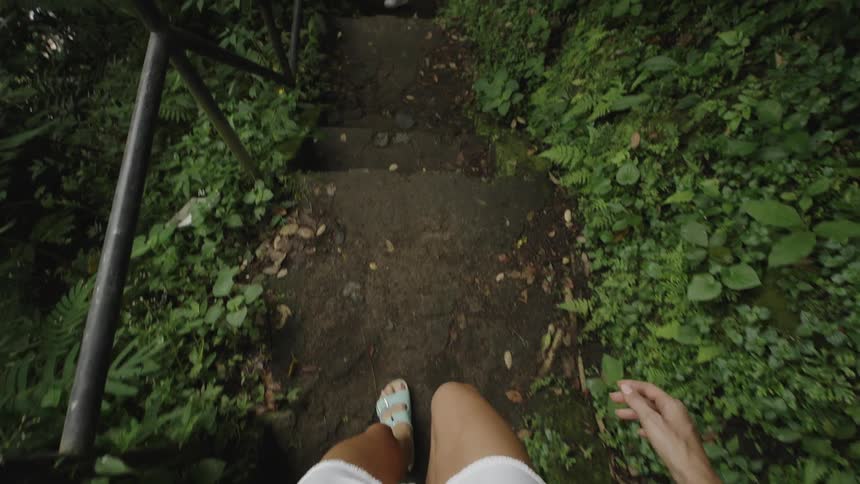 Womans point of view walking down the stairs on a trail through a forest