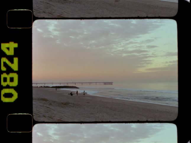 People are walking on the beach at sunrise