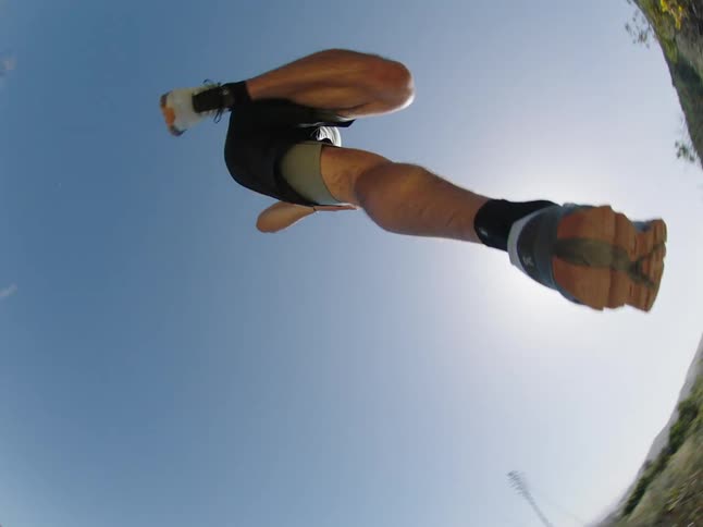 A man runs along a dirt trail and takes a giant leap in slow motion