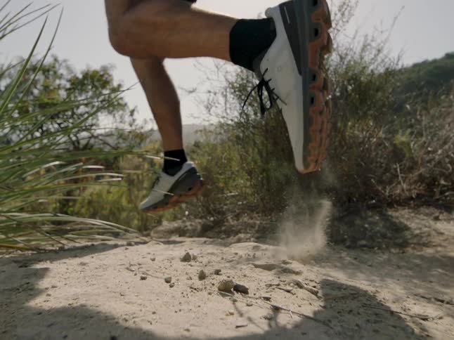 A white man runs over a dirt path in a nature