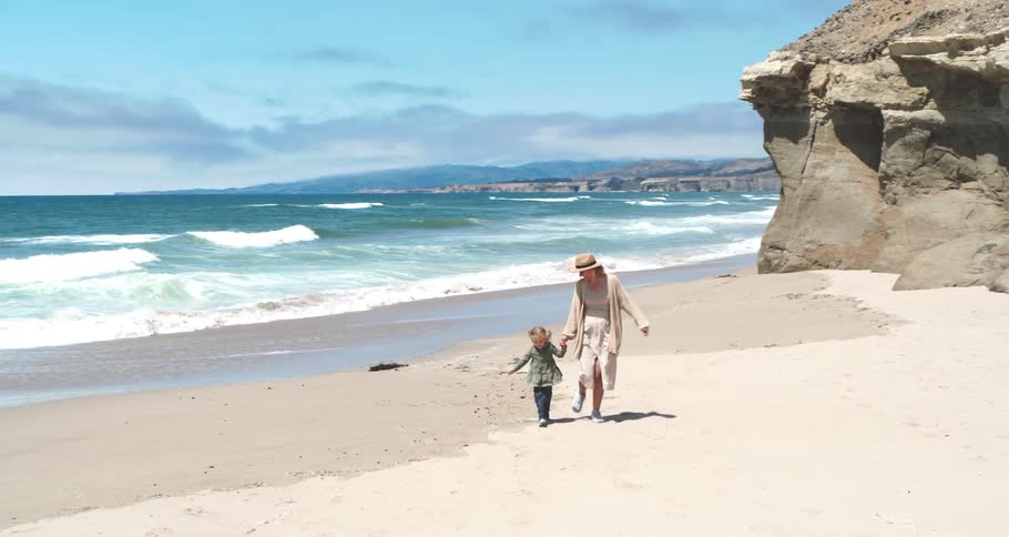 Mother with her daughter running on the sand at the beach