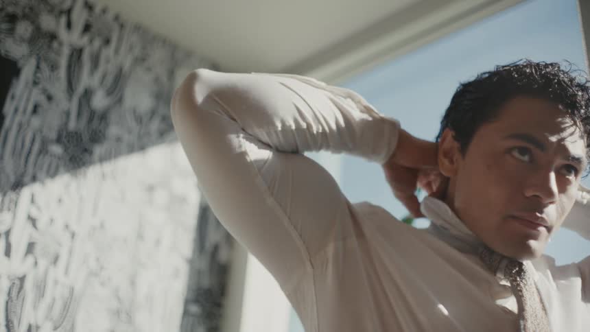 Man in an indoor room adjusting his tie