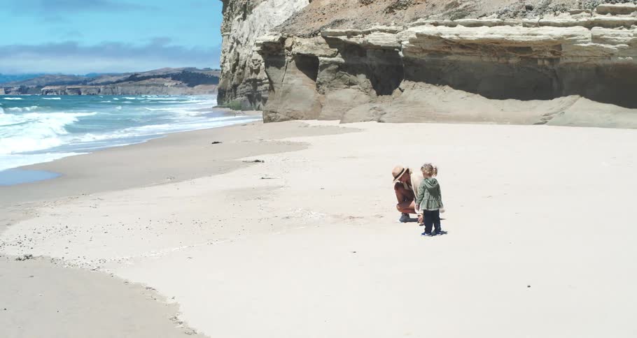 Mother and daughter playing in the sand on the beach