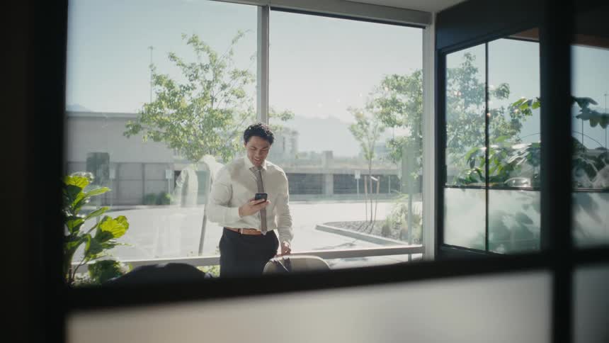 Man in an office room hanging up the phone call and jumping for joy
