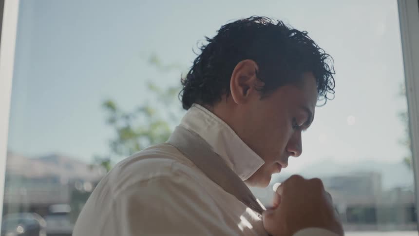 Man putting on a tie and adjusting his shirt