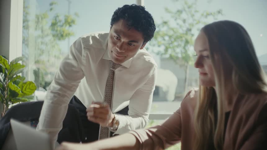 Man and woman talking at an office desk with a laptop