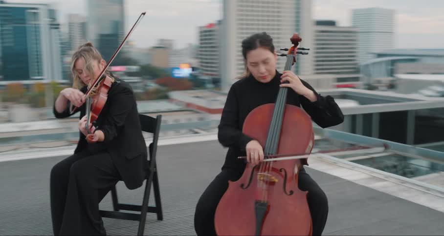 Group sitting in chairs on the terrace of a building playing the violin