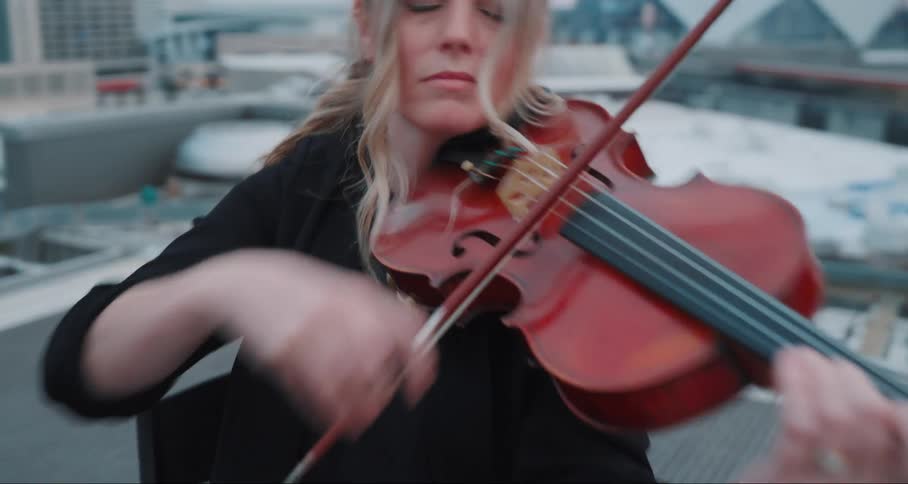 Woman on a terrace of a building playing a violin