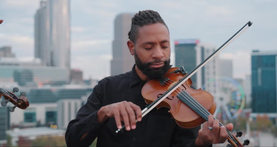 Man on the terrace of a building playing the violin
