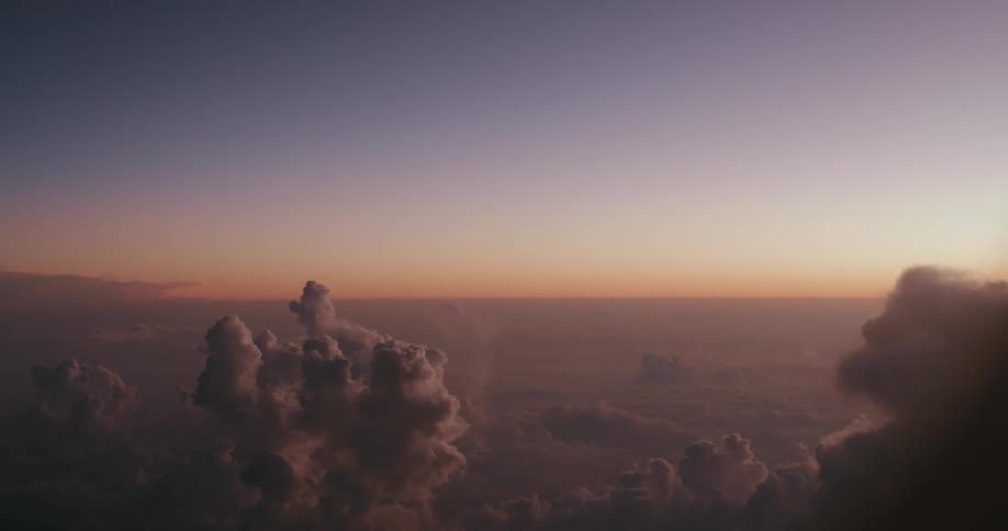 Aerial shot of a sea of clouds with the sky in shades of purple and red