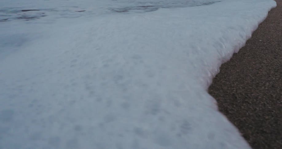 The waves leave foam on the beach