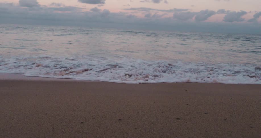 Foamy water reaching the beach sand at dawn
