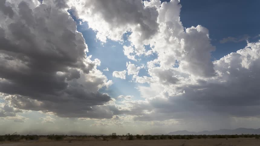 A vast desert landscape storm clouds with rain falling in the distance