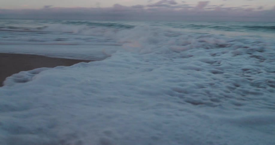 Waves with foam reaching the beach sand one morning