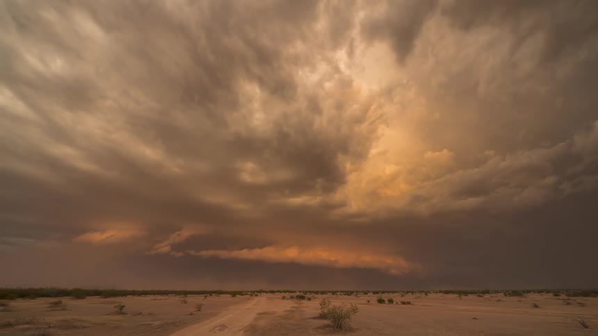 A tornado is starting to form in a very cloudy sky over an empty desert