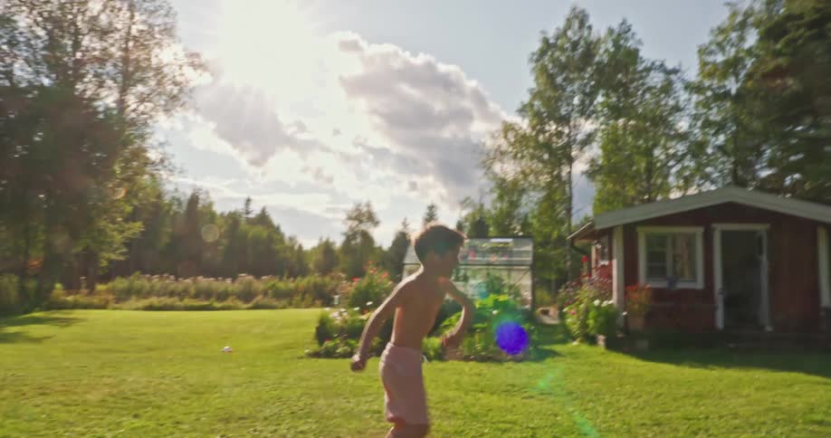 A child playing and dancing by himself on a grassy field during daytime under clear skies