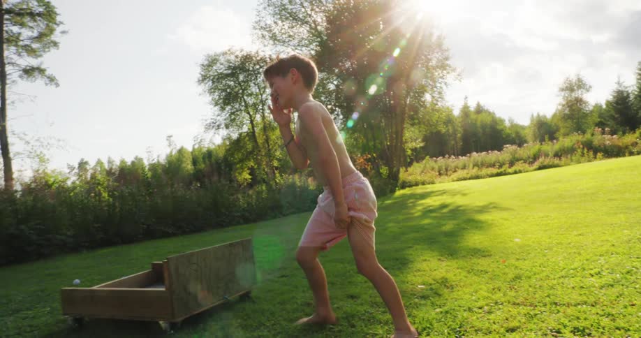 Cheerful boy getting up from the grass and catching a soccer ball