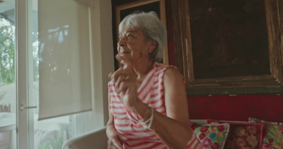 An elderly woman in workout attire dancing in a welllit living room