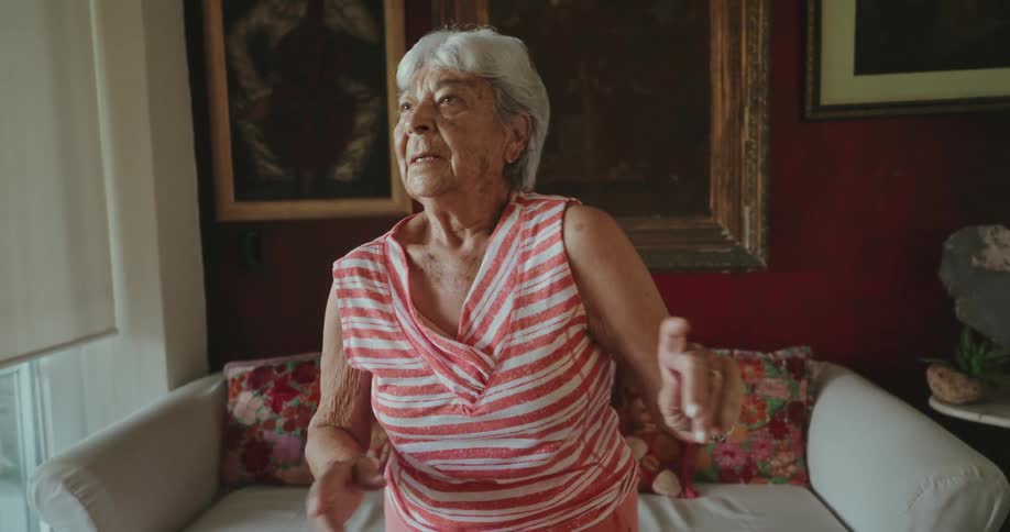 Elderly woman dances alone at home in her living room