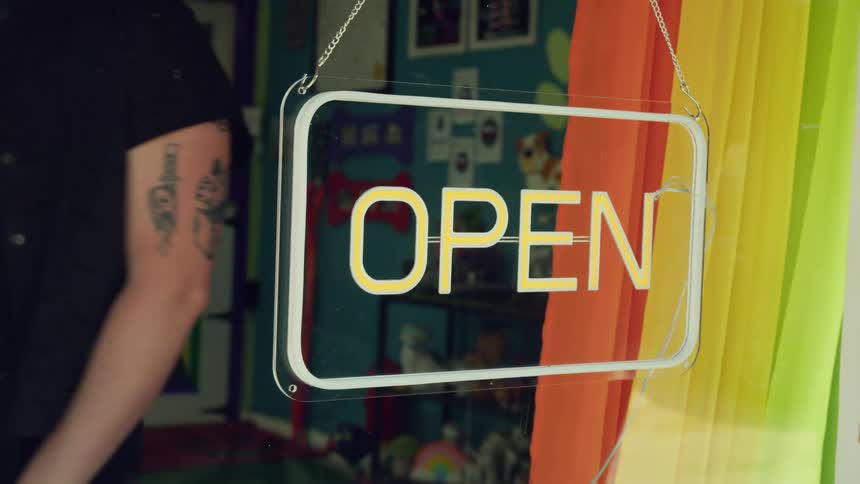 Person closing up shop and turning the neon open sign off to indicate the shop is closed.