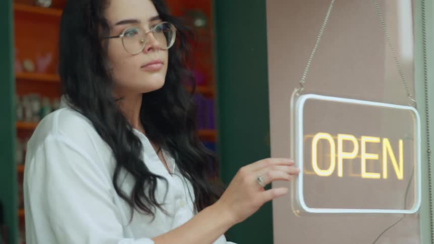 Woman turning on a neon sign board of a store