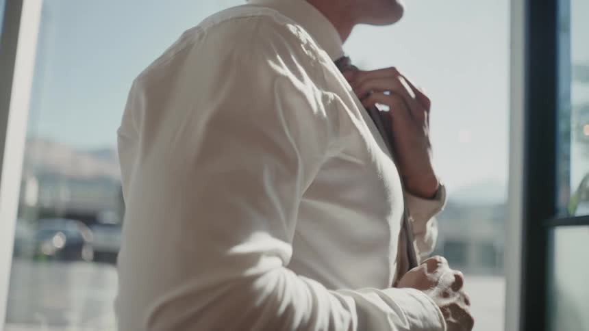 Man indoors adjusting his tie
