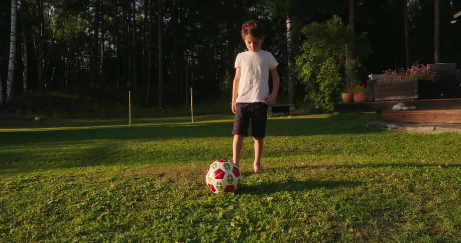 A young boy kicking a soccer ball on a grassy field