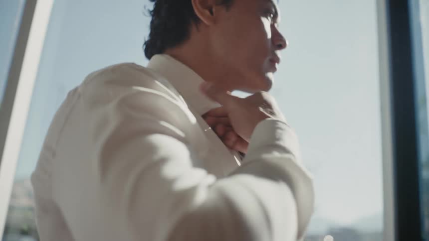 Portrait of a man indoors adjusting his tie