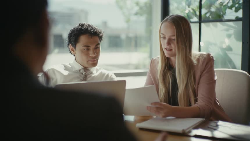 Three people sitting at an office table discussing a document